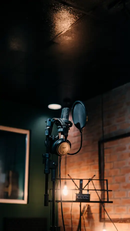A microphone and headphones in a dim recording room.